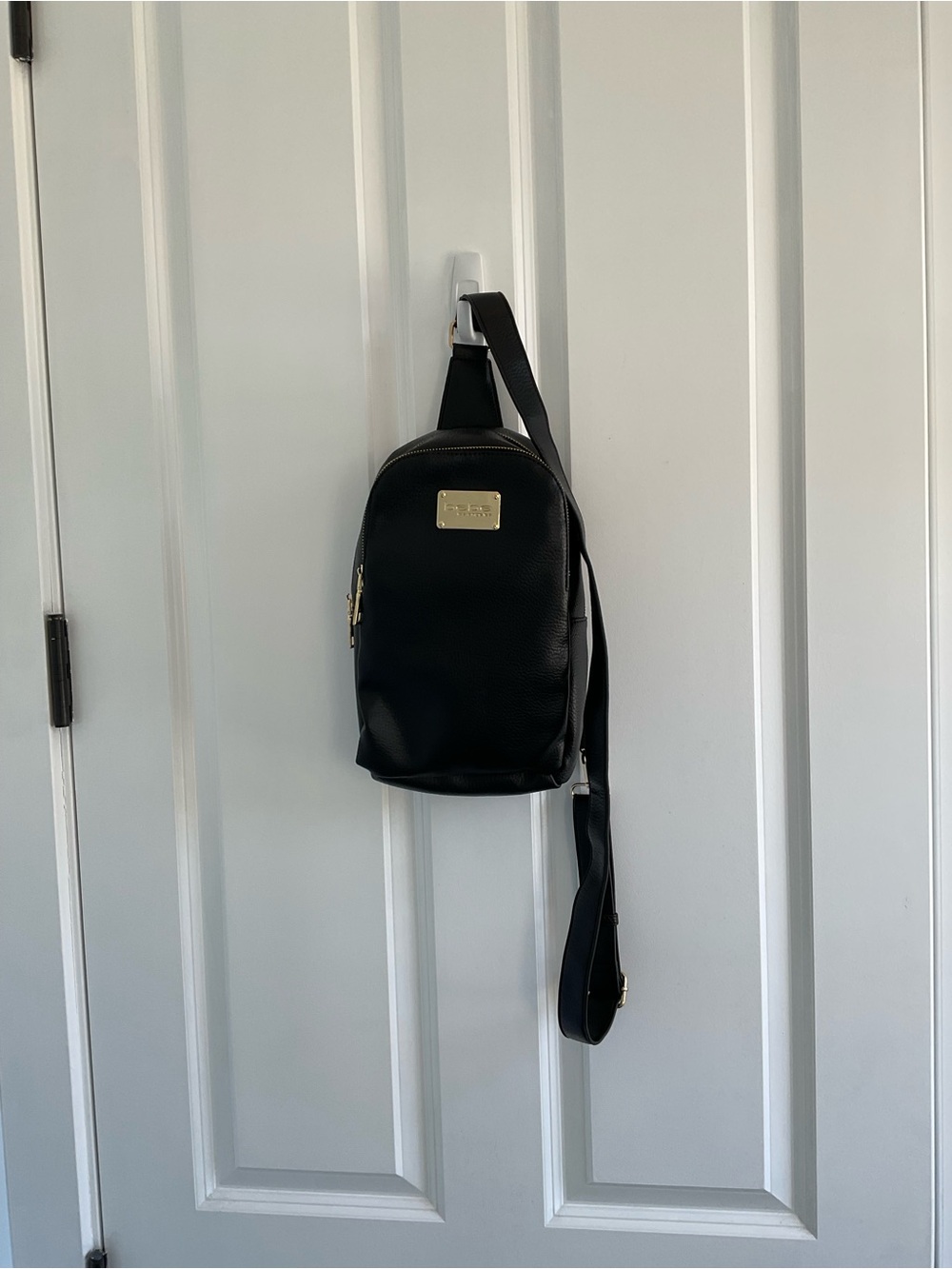 bebe Yolanda  Black Pebbled Vegan Leather Sling Backpack with Gold Tone Zippers